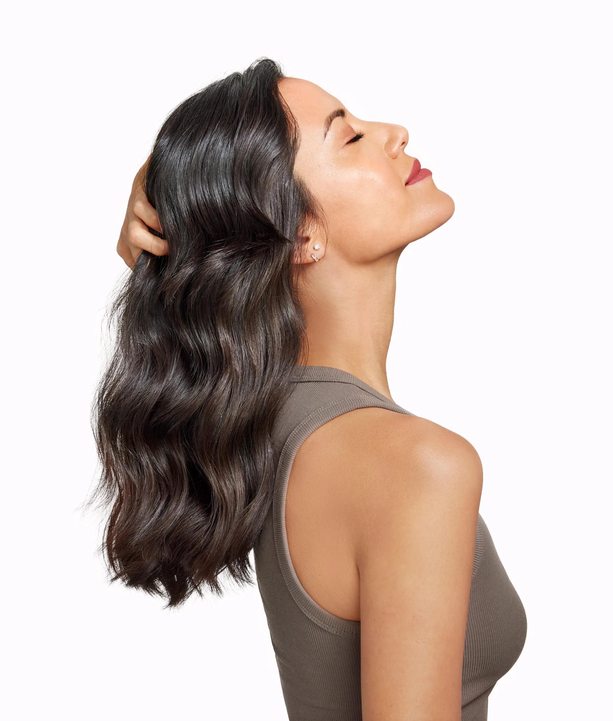 profilo laterale di una donna bruna con la testa reclinata all'indietro e che si afferra i capelli